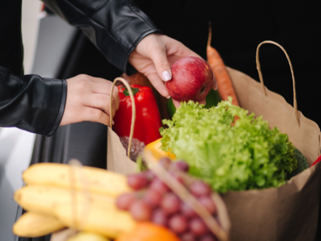 Papieren tassen met boodschappen zoals appels wortel en sla