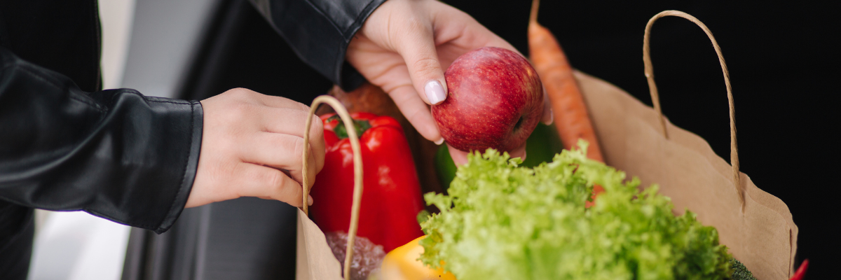 Papieren tassen met boodschappen zoals appels wortel en sla